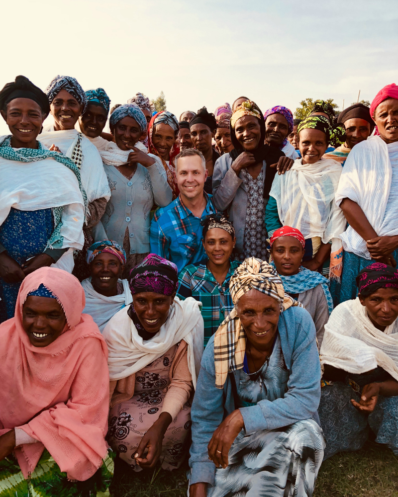 A man stands among a group of smiling Ethiopian women.