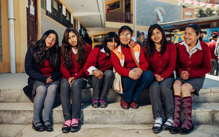 Une femme membre de Vision Mondiale, assise avec un groupe de cinq élèves du secondaire.