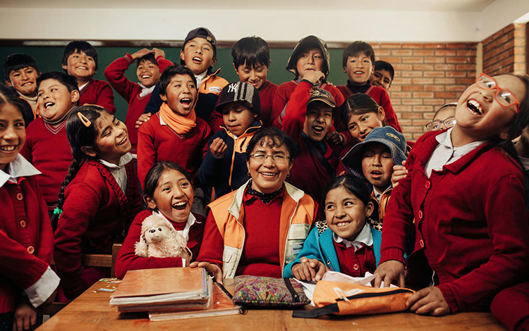 Une femme entourée d’un groupe d’élèves dans une salle de classe en Bolivie.
